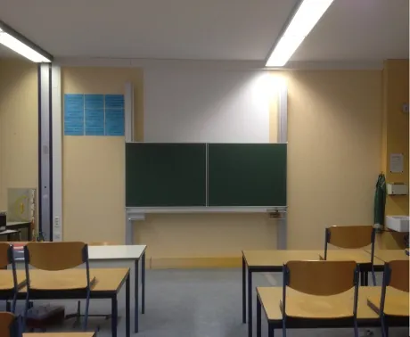 Klassenzimmer mit gelben Wänden und geschlossener grüner Klapptafel